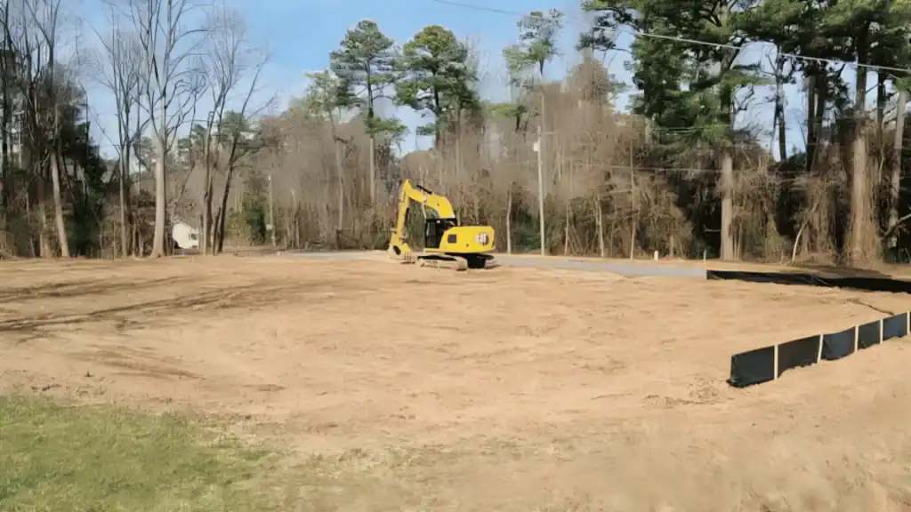 A yellow excavator in a dirt field, ideal for both commercial excavation Virginia and residential excavation Virginia projects.